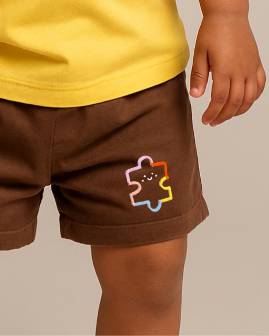 Brown shorts with a colorful logo worn by a child, on a neutral background