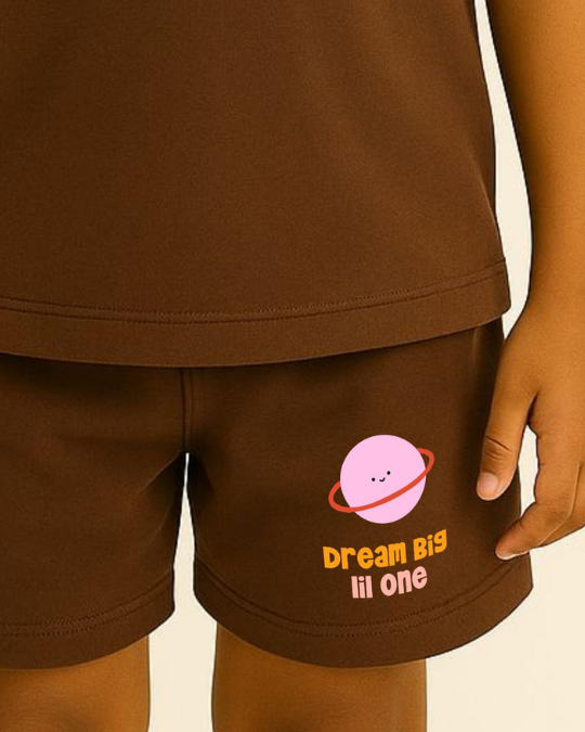 Brown shorts with a pink planet design and 'Dream Big lil one' text on a beige background
