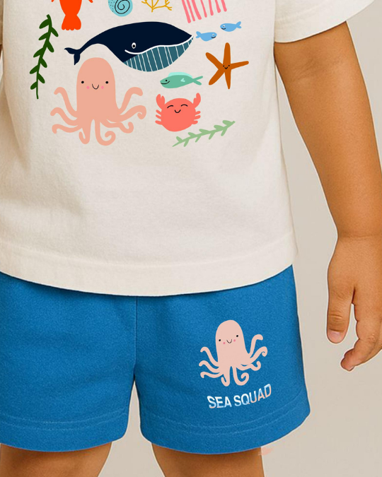 Child wearing a t-shirt with sea-themed graphics and blue shorts with an octopus design.