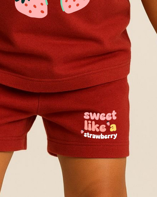 Red shorts with 'sweet like a strawberry' text and strawberry design on a beige background