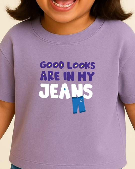Child wearing a purple t-shirt with 'Good looks are in my jeans' text and graphic.