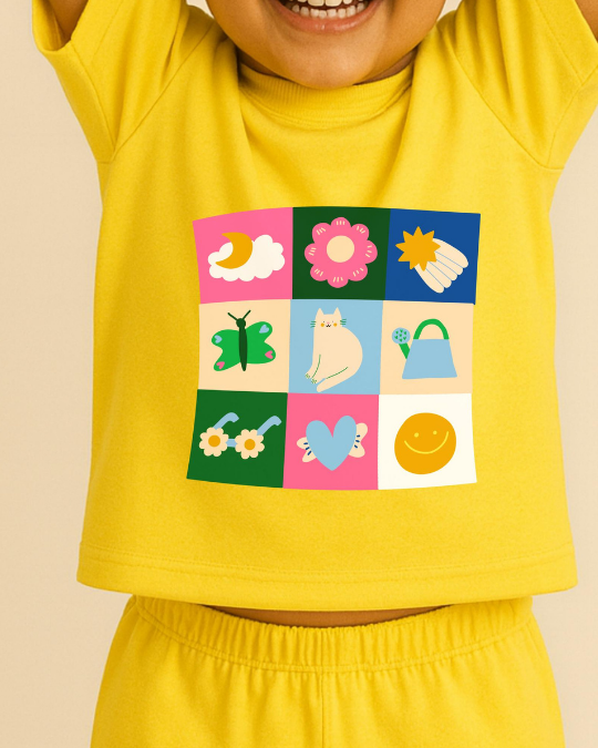 Child wearing a yellow outfit with a colorful patch featuring various illustrations on a beige background