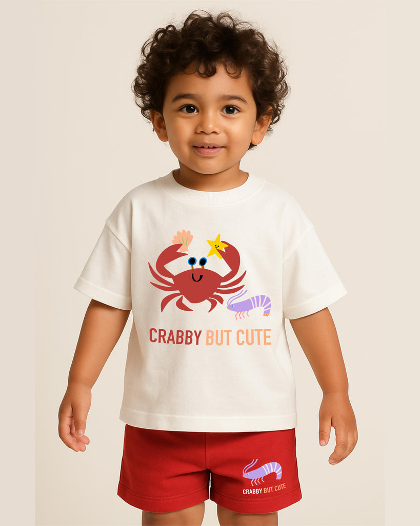 Child wearing a white t-shirt with a red crab graphic and text, standing against a plain background.