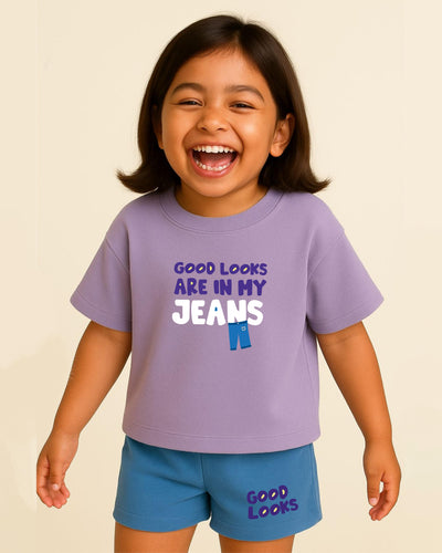 Child wearing a purple t-shirt with 'Good looks are in my jeans' text on a beige background