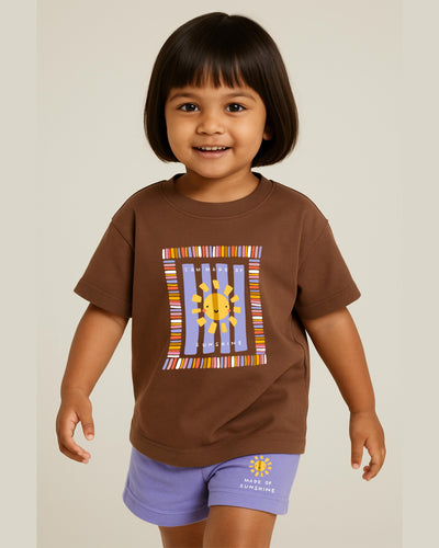 Child wearing a brown t-shirt with a colorful sun design on a plain background