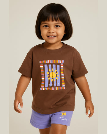Child wearing a brown t-shirt with a colorful sun design on a plain background