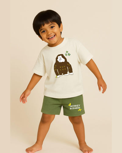 Child wearing a white t-shirt with a monkey graphic and green shorts with 'Monkey Business' text on a beige background
