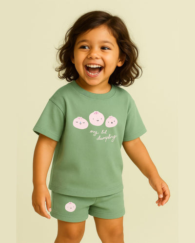 Child wearing a green outfit with dumpling designs on a beige background