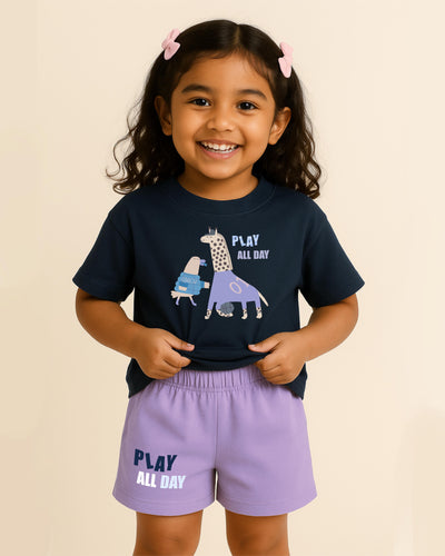 Child wearing a navy t-shirt and purple shorts with 'Play All Day' text on a beige background