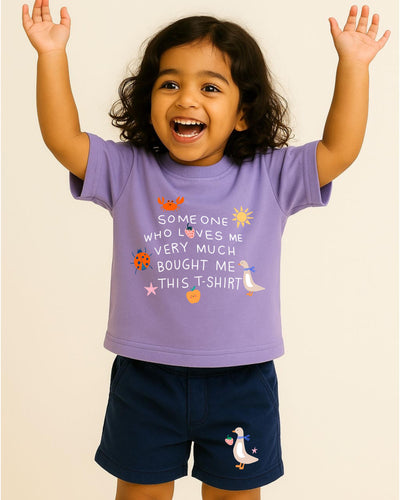 Child wearing a purple t-shirt with text and graphics, standing against a plain background