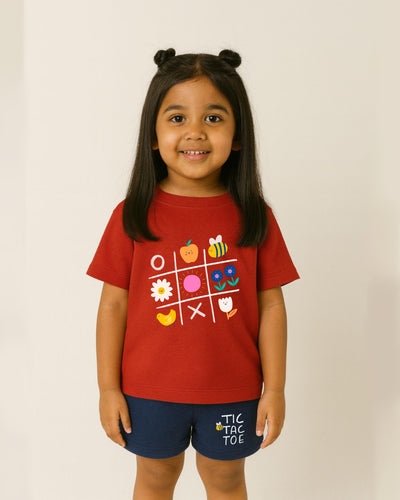 Child wearing a red t-shirt with colorful graphics and blue shorts on a plain background