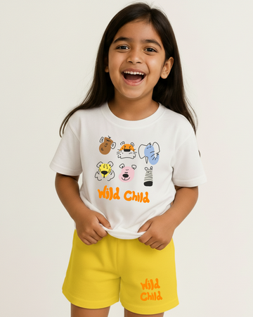 Child wearing a white t-shirt with cartoon animals and yellow shorts with text, on a plain background