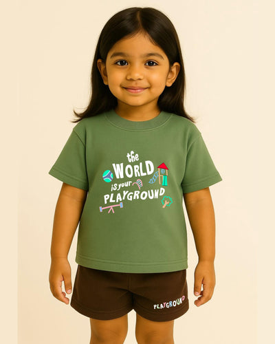 Child wearing a green t-shirt with 'The World is Your Playground' text and graphics on a beige background